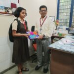 Rujul and Principal of IES Mulund pose for a photo in classroom near desk..